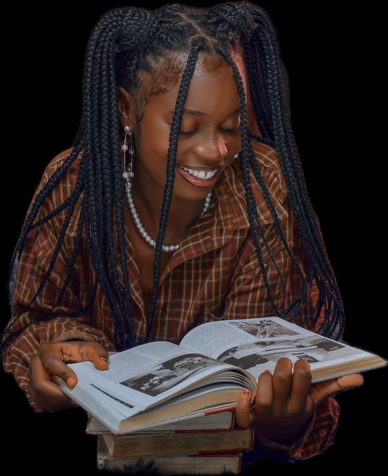 A student smiling as she reads an open book from a stack
