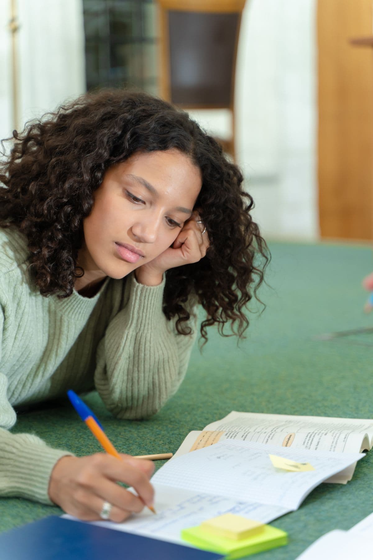 A student writing in a notebook with sticky notes beside her